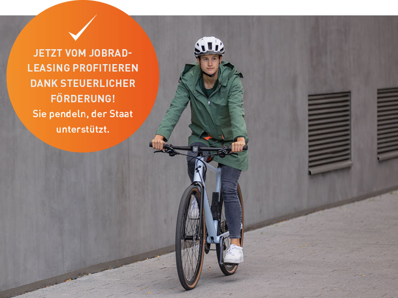 zweiradleasing-am-bodensee-radfahrer-stadtrad-pendler-4 Ein Radfahrer mit grüner Parka-Jacke fährt auf einem Stadtrad durch eine graue Landschaft. Über dem Bild ist ein Button zu sehen. Aufschrift dessen ist: "Jetzt vom Jobrad-Leasing profitieren dank steuerlicher Förderung! Sie pendeln, der Staat unterstützt."